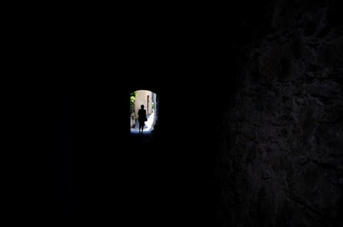 Woman Walking in a Dark Tunnel with Sunlight in Gandria, Ticino, Switzerland, Europe
