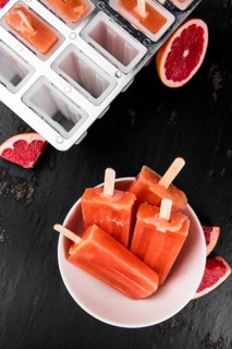 Vintage slate slab with some freshly made Grapefruit Popsicles (selective focus, close-up shot)