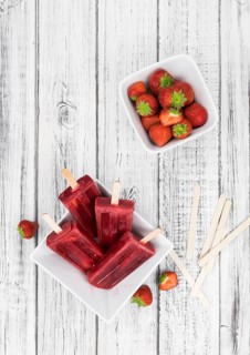 Homemade Strawberry Popsicles (close-up shot, selective focus) on vintage background