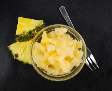 Portion of Preserved Pineapple (chopped) as detailed close up shot on a slate slab, selective focus