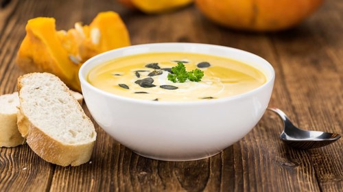 Portion of fresh made Pumpkin Soup (close-up shot) on rustic background