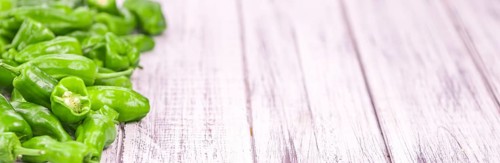 Raw Pimientos on rustic wooden background as close-up shot