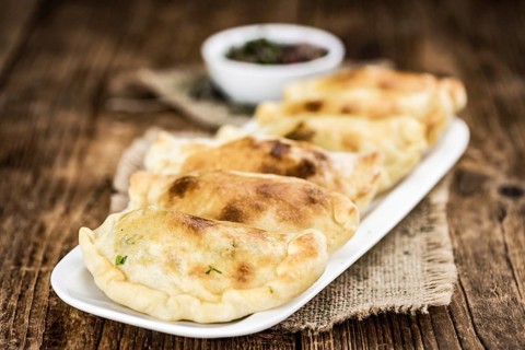 Wooden table with fresh homemade Empanadas (detailed close-up shot, selective focus)