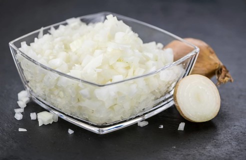 Some White Onions (dices) on a slate slab as detailed close-up shot, selective focus