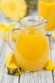 Pineapple Juice as high detailed close-up shot on a vintage wooden table, selective focus