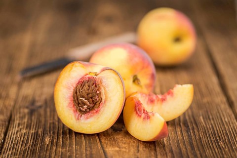 Fresh Peaches as high detailed close-up shot on a vintage wooden table, selective focus