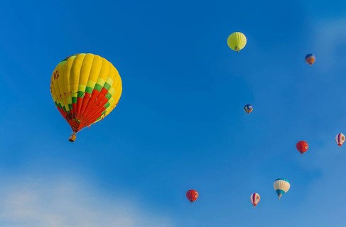 Several hot air balloons of various colors floating in a clear blue sky, Belarus, Minsk, Europe