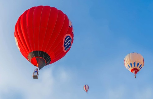 Hot air balloons of red and white colors float against a clear blue sky, Belarus, Minsk, Europe