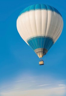 A hot air balloon with a blue and white pattern floats peacefully in a clear blue sky, Belarus,