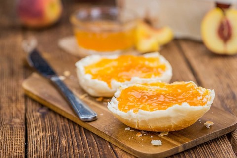 Peach Jam on an old wooden table as detailed close-up shot, selective focus