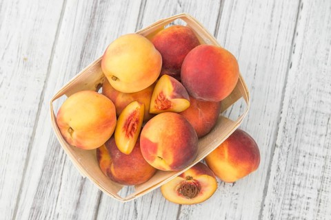Fresh Peaches as high detailed close-up shot on a vintage wooden table, selective focus