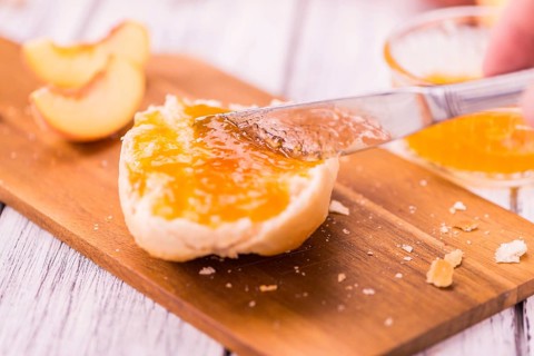 Peach Jam on an old wooden table as detailed close-up shot, selective focus