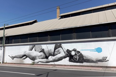 Reclining woman in bikini with diving mask, surreal mural in black and white by Greek street artist