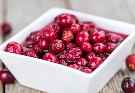 Old wooden table with fresh Preserved Cranberries (close-up shot, selective focus)