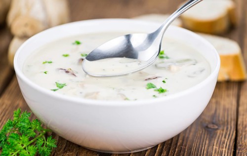 Homemade Porcini Soup on an wooden table as detailed close-up shot, selective focus