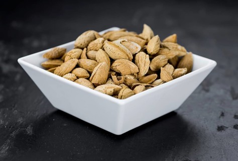 Portion of roasted Almonds (in the shell) on a dark slate slab as detailed close-up shot (selective