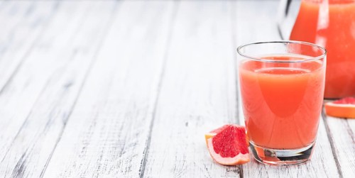 Some freshly squeezed Grapefruit Juice on a vintage background (close-up shot, selective focus)