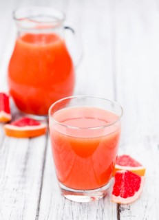 Vintage wooden table with a portion of freshly squeezed Grapefruit Juice (selective focus)