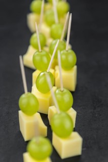 Cheese blocks with grapes as close-up shot on a vintage looking slate slab (selective focus,