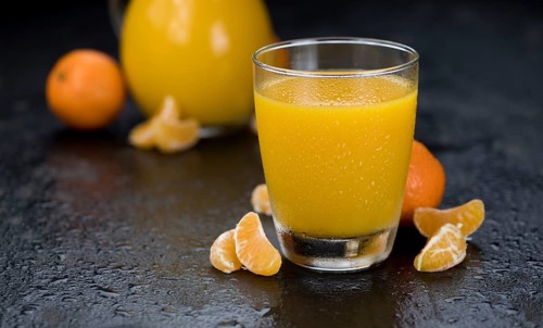 Portion of fresh made Tangerine Juice (close-up shot, selective focus)