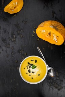 Portion of fresh made Pumpkin Soup (close-up shot) on rustic background