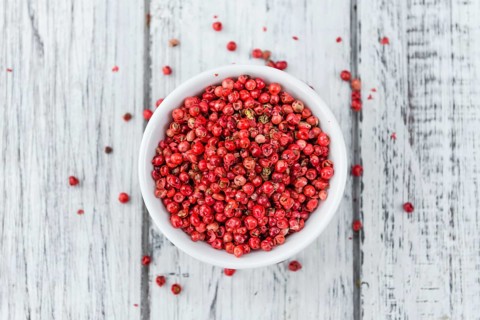 Pink Peppercorns on an old wooden table as detailed close-up shot, selective focus