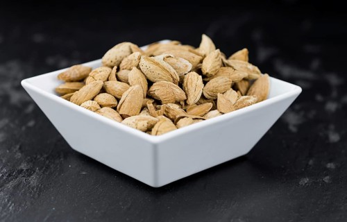 Roasted and salted Almonds (with shell) on a vintage background (close-up shot)