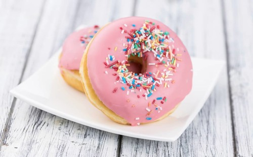 Portion of pink glazed Donuts (detailed close-up shot)