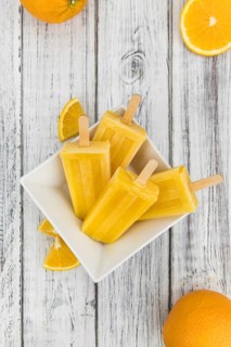 Orange Popsicles (selective focus, close-up shot) on a vintage background