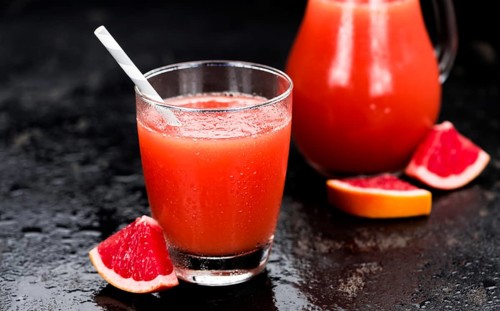 Some freshly squeezed Grapefruit Juice on a vintage background (close-up shot, selective focus)