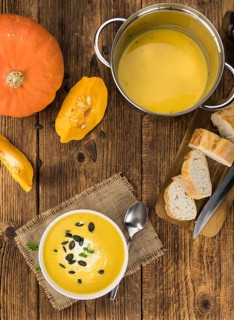 Portion of fresh made Pumpkin Soup (close-up shot) on rustic background