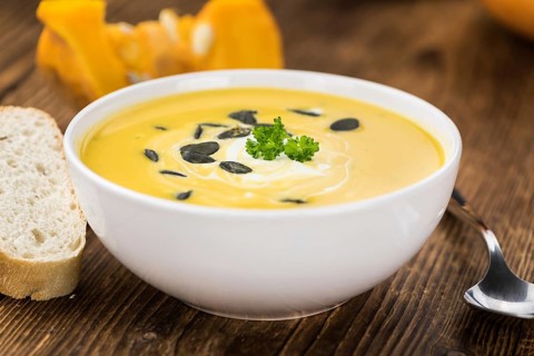 Portion of fresh made Pumpkin Soup (close-up shot) on rustic background