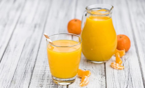 Wooden table with fresh homemade Tangerine Juice (close-up shot, selective focus)