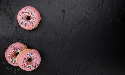 Portion of pink glazed Donuts (detailed close-up shot)