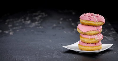 Portion of pink glazed Donuts (detailed close-up shot)