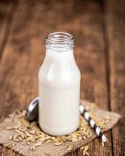 Healthy Oat Milk on a wooden table as detailed close-up shot (selective focus)