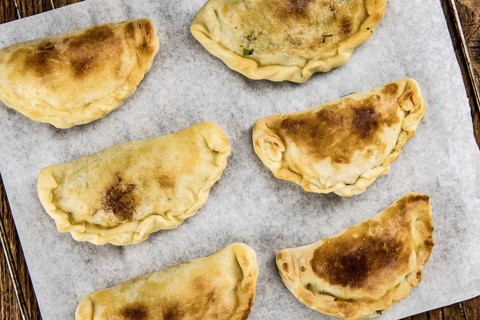 Wooden table with fresh homemade Empanadas (detailed close-up shot, selective focus)