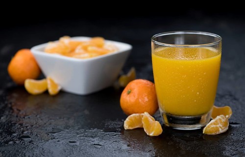 Portion of fresh made Tangerine Juice (close-up shot, selective focus)