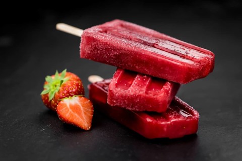 Homemade Strawberry Popsicles (close-up shot, selective focus) on vintage background