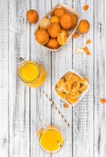 Wooden table with fresh homemade Tangerine Juice (close-up shot, selective focus)