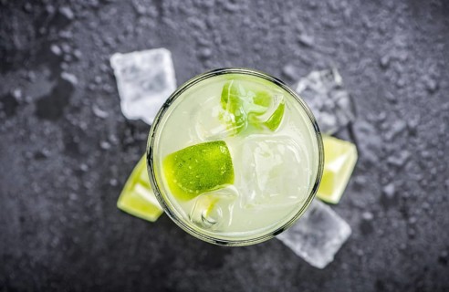 Caipirinha made with fresh limes, ice and sugar as close-up shot