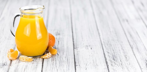 Wooden table with fresh homemade Tangerine Juice (close-up shot, selective focus)