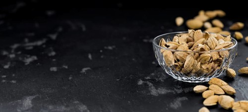 Almonds in shell (roasted and salted) on a vintage background (close-up shot)