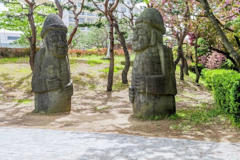 Two large stone statues standing in a park with trees around, in Suncheon, South Korea, Asia