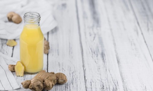 Healthy Ginger Sap on a wooden table as detailed close-up shot (selective focus)
