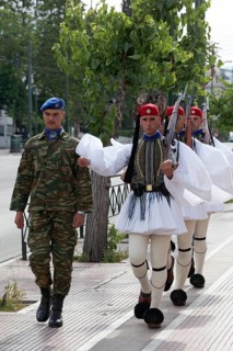 Evzones march on the pavement for the changing of the guard in front of the parliament building,