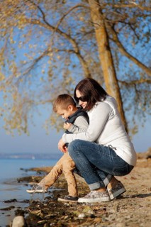 A woman and a child are kneeling by a lakeshore in autumn, enjoying the nature and calm atmosphere,