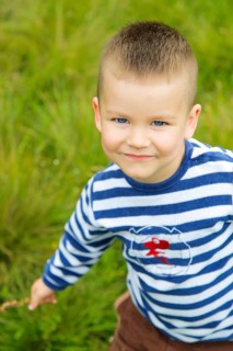 A smiling boy wearing a striped shirt outdoors on a grassy field.Belarus.Minsk