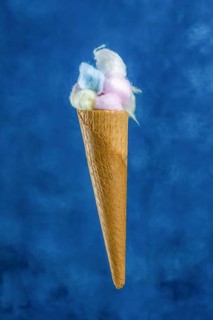Different colored cotton balls in an ice cream cone on a blue background