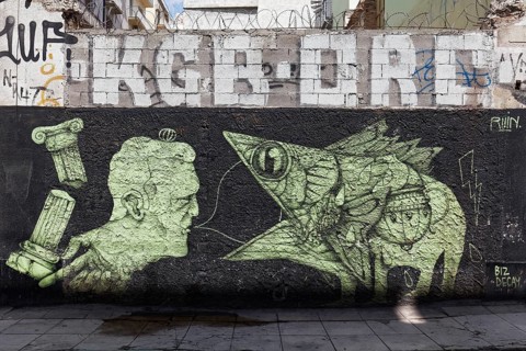 Man talks to fish, fish swallows speech bubble, surreal mural by street artist Ruin, Exarchia